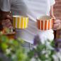 Preview: Musango Zwei handgefertigte Tassen mit Streifenmuster, in Gelb und Orange, Outdoor-Lifestyle-Szene