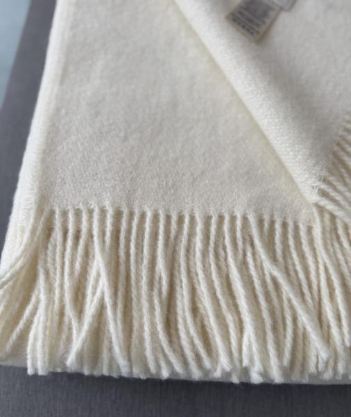 Gefaltete cremeweisse Kuscheldecke Gant mit dekorativem Fransenabschluss